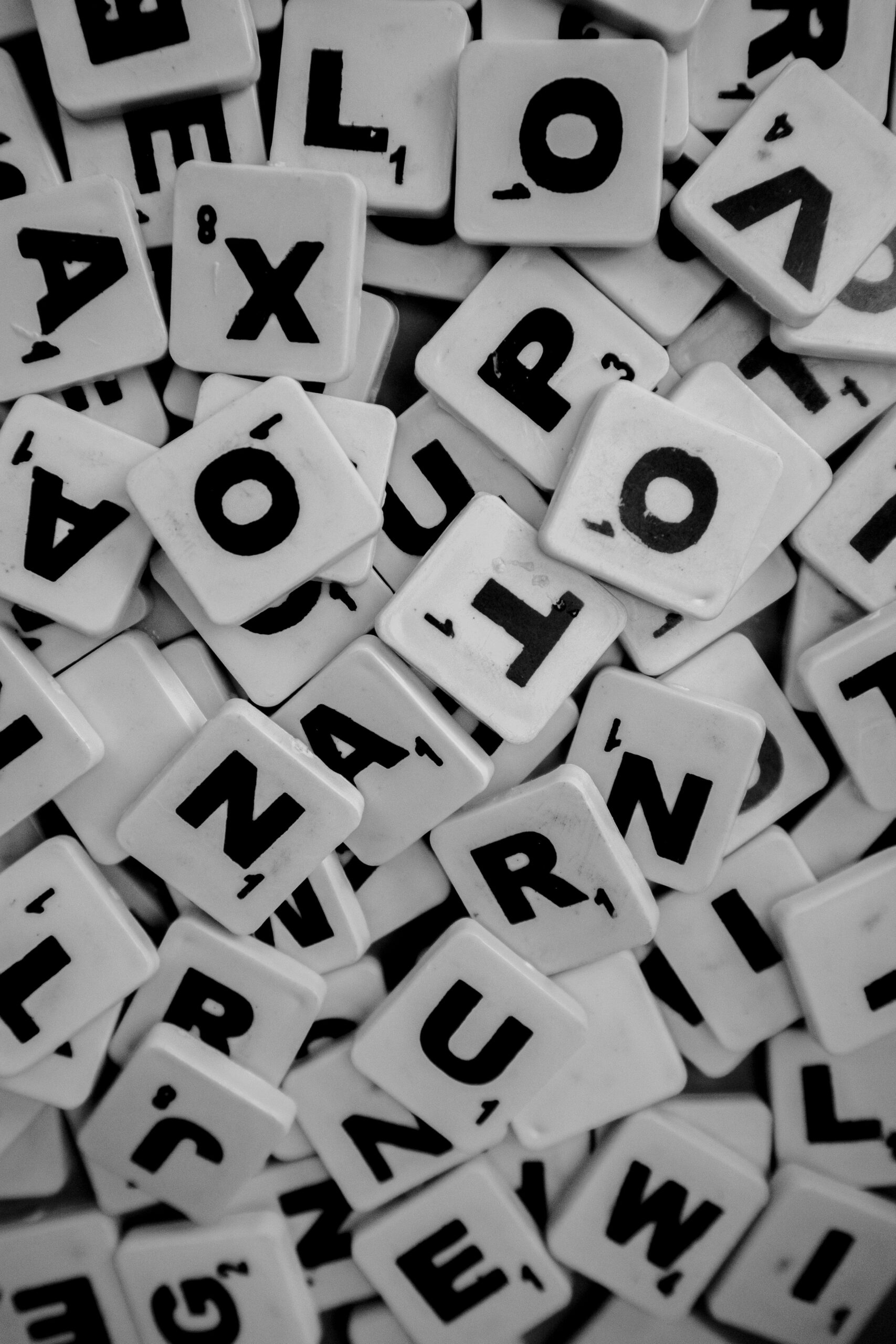 Close-up of a pile of Scrabble tiles showing different letters in black and white.