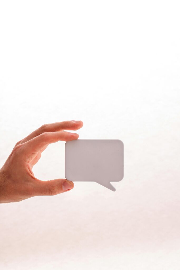A minimalist image of a hand holding a blank speech bubble icon, ideal for communication themes.